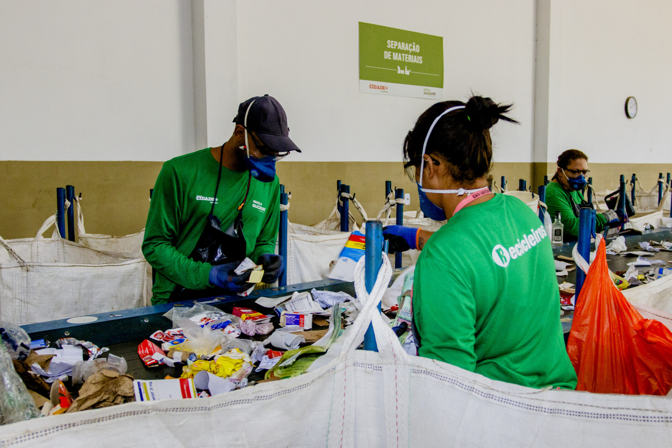 esteira de reciclagem cooperativa Recicla Guaxupé com dois colaboradores selecionando materiais recicláveis.